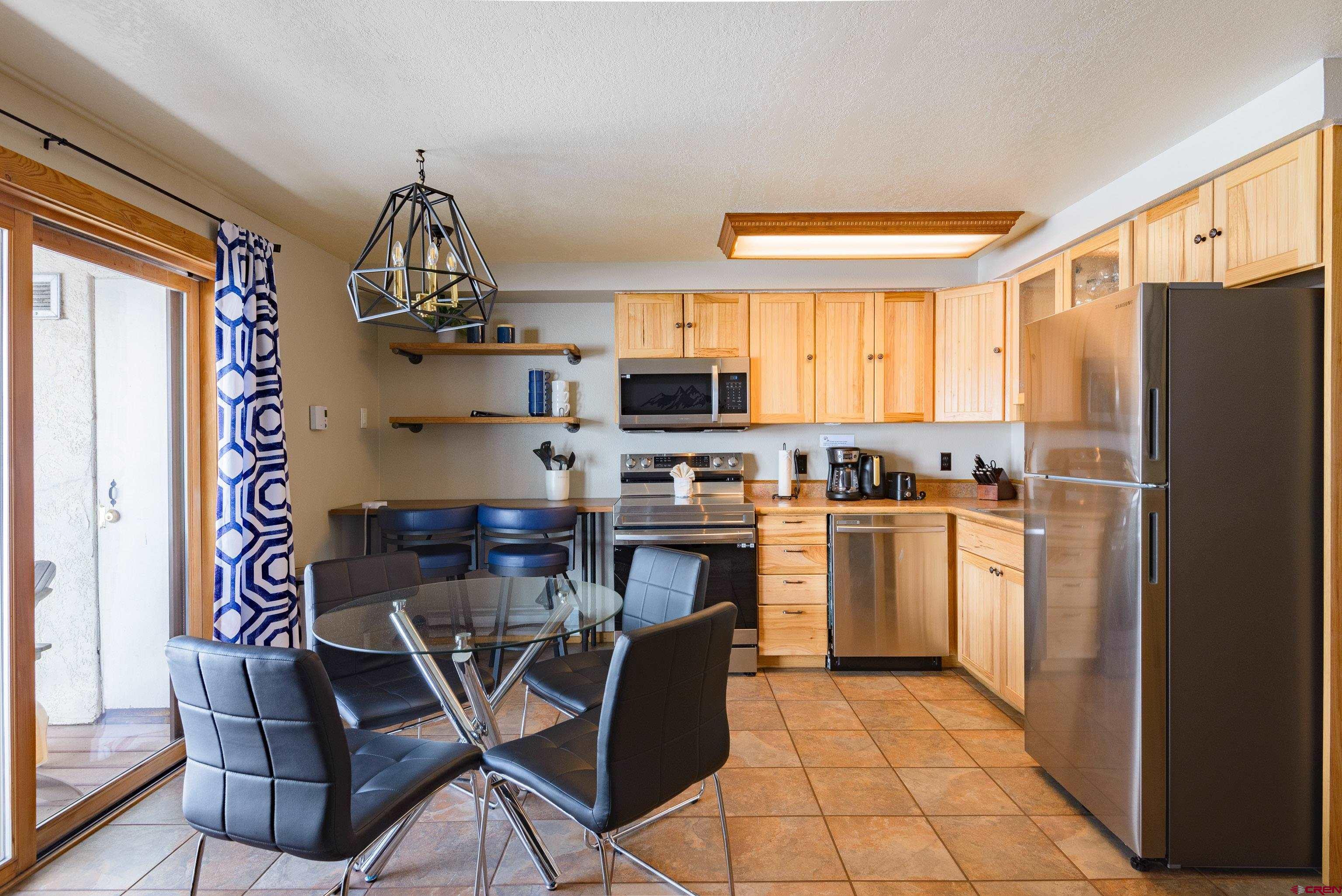 701 Gothic Road, Unit 306 Crested Butte, CO 81225 - Photo 3 of 25 a kitchen with stainless steel appliances a refrigerator a stove a sink cabinets and a dining table
