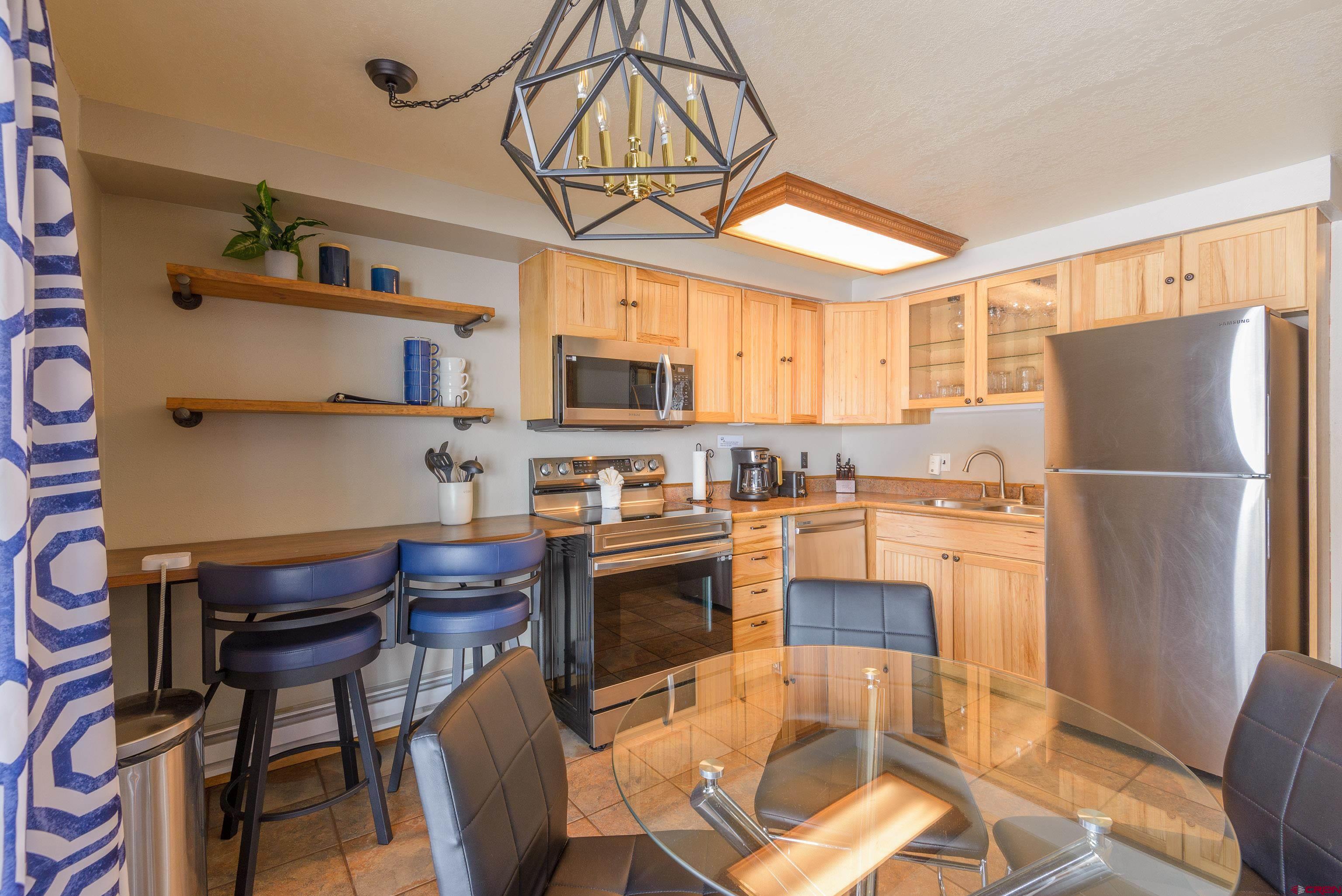 701 Gothic Road, Unit 306 Crested Butte, CO 81225 - Photo 4 of 25 a kitchen with stainless steel appliances granite countertop a refrigerator a stove top oven a sink dishwasher and a dining table with wooden floor