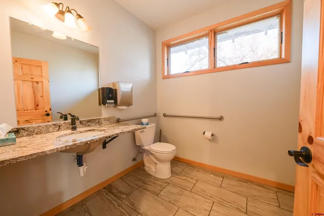 a bathroom with a granite countertop toilet sink and mirror