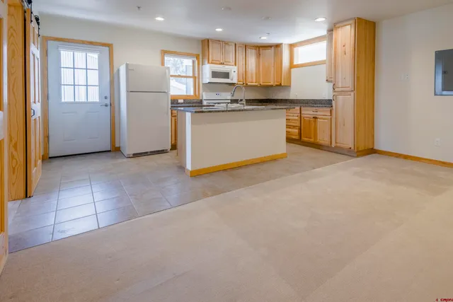 a view of kitchen with stainless steel appliances granite countertop a refrigerator a sink dishwasher with a dining table and chairs