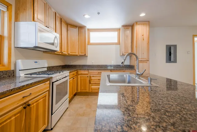 a kitchen with stainless steel appliances granite countertop a sink a stove top oven a counter space and cabinets