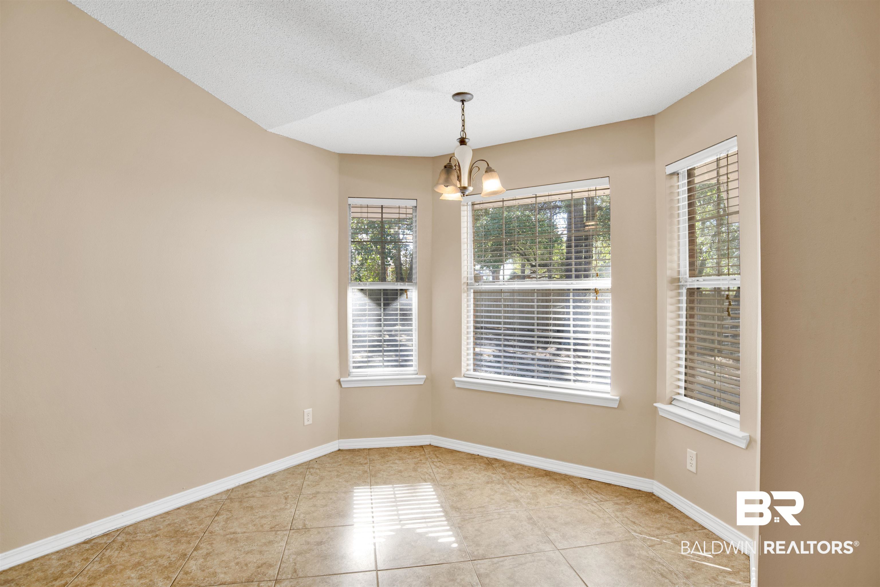 7297 Bridgemill Drive Mobile, AL 36619 - Photo 10 of 33 Unfurnished dining area featuring a chandelier, a textured ceiling, and light tile patterned floors
