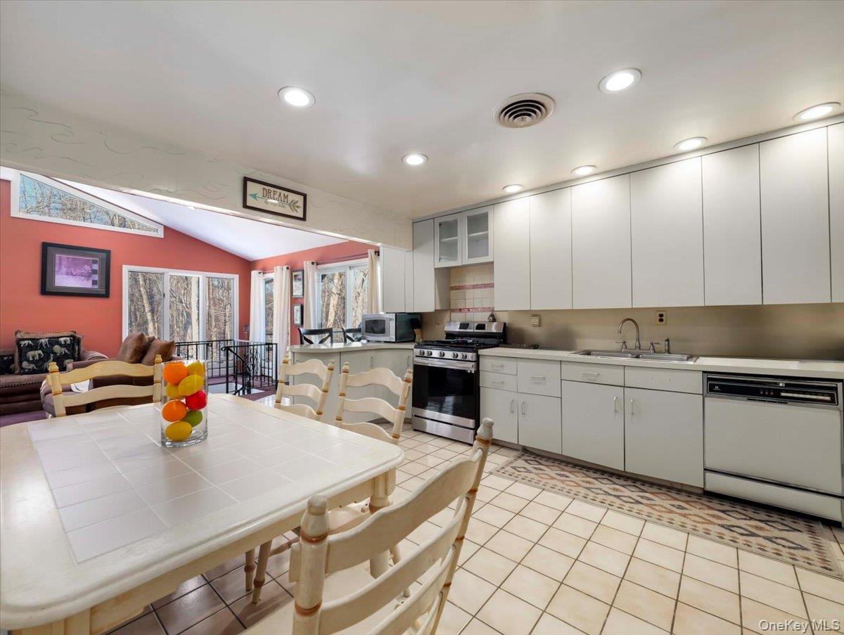 13 Razel Avenue Spring Valley, NY 10977 - Photo 14 of 43 a kitchen with stainless steel appliances granite countertop a sink a stove white cabinets with a dining table and chairs