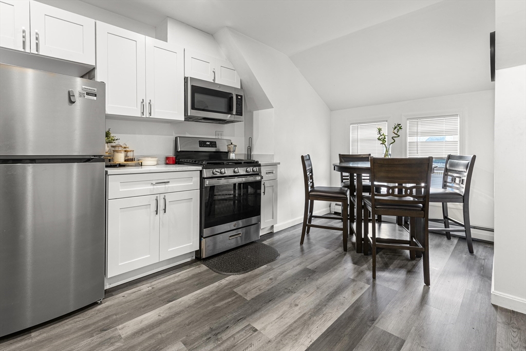 139-141 Foster Street Lawrence, MA 01843 - Photo 9 of 16 a kitchen with stainless steel appliances a dining table chairs microwave and refrigerator