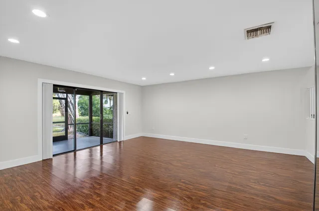a view of empty room with wooden floor and floor to ceiling window