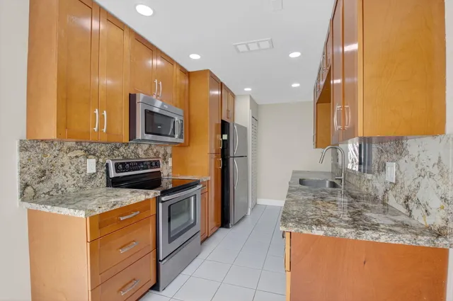 a kitchen with stainless steel appliances granite countertop a refrigerator and a sink