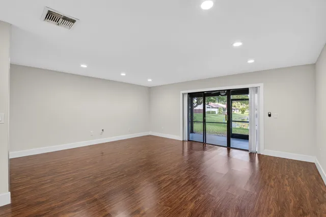 an empty room with wooden floor and window