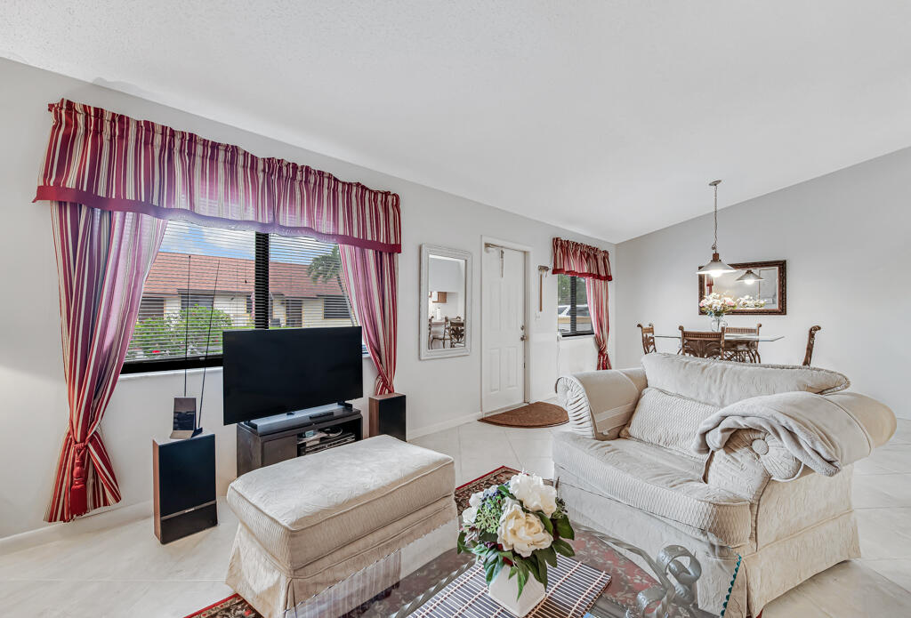815 Andrew Redding Road, Unit 202 Lantana, FL 33462 - Photo 8 of 30 a living room with furniture a flat screen tv and a floor to ceiling window
