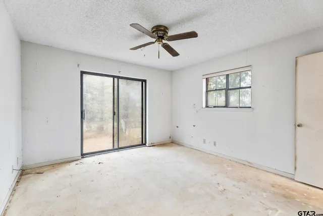 an empty room with fan and windows