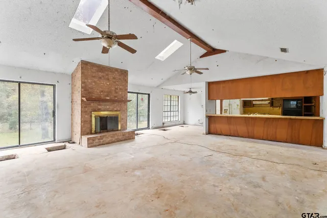 a view of an empty room with a fireplace and a window