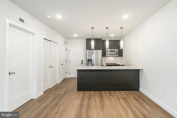 a large white kitchen with kitchen island a sink stainless steel appliances and cabinets