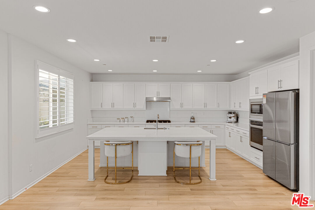 24477 Oneida Street Moreno Valley, CA 92553 - Photo 17 of 51 a kitchen with stainless steel appliances granite countertop a table chairs sink refrigerator and cabinets