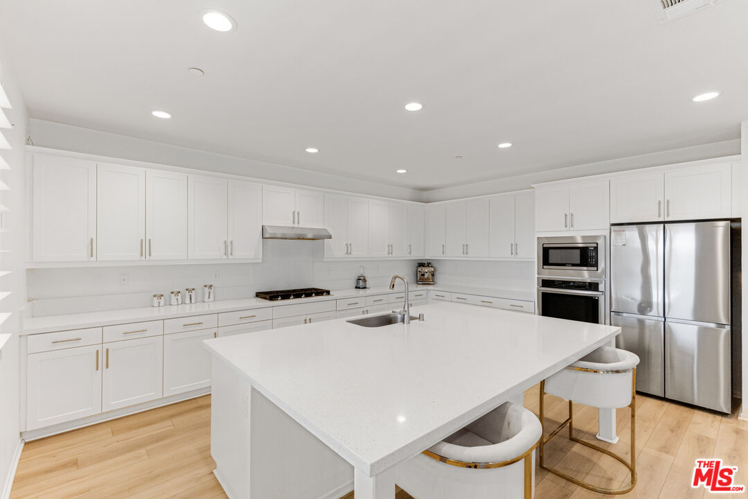 24477 Oneida Street Moreno Valley, CA 92553 - Photo 18 of 51 a kitchen with a sink a stove a refrigerator and white cabinets