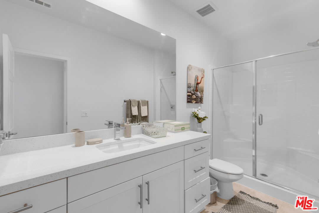 24477 Oneida Street Moreno Valley, CA 92553 - Photo 34 of 51 a bathroom with a toilet a sink a mirror a shower a vanity and window