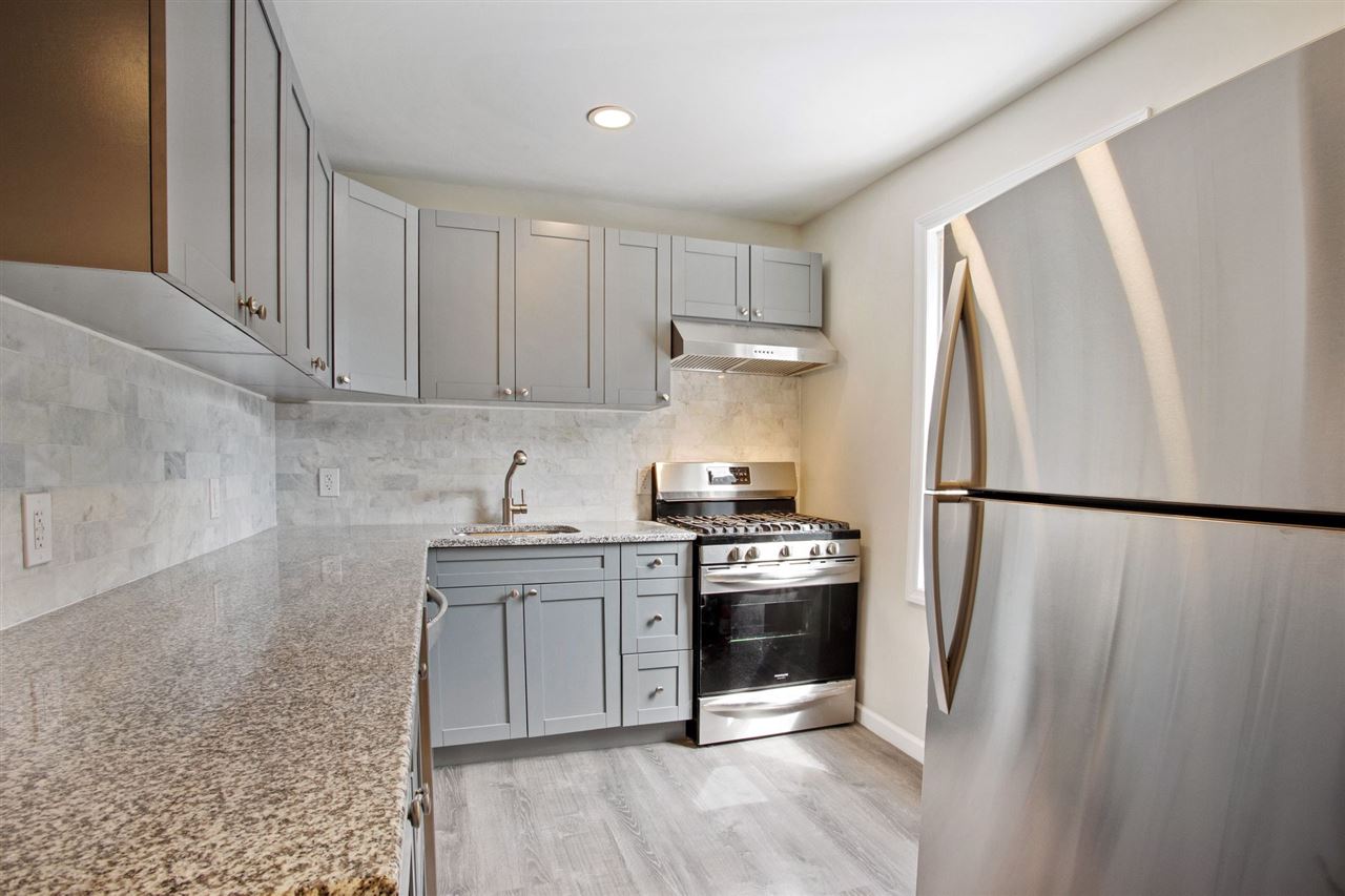 a kitchen with stainless steel appliances a refrigerator a stove a sink and white cabinets