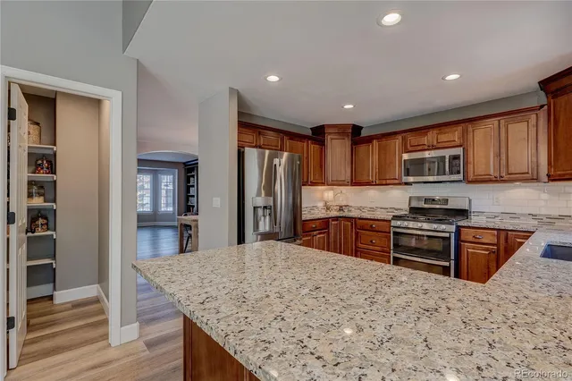 a kitchen with stainless steel appliances granite countertop a stove refrigerator and cabinets