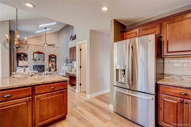 a kitchen with stainless steel appliances granite countertop a refrigerator a sink and white cabinets