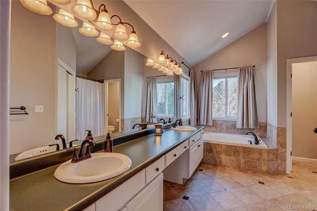 a bathroom with double vanity sinks a mirror and a bathtub