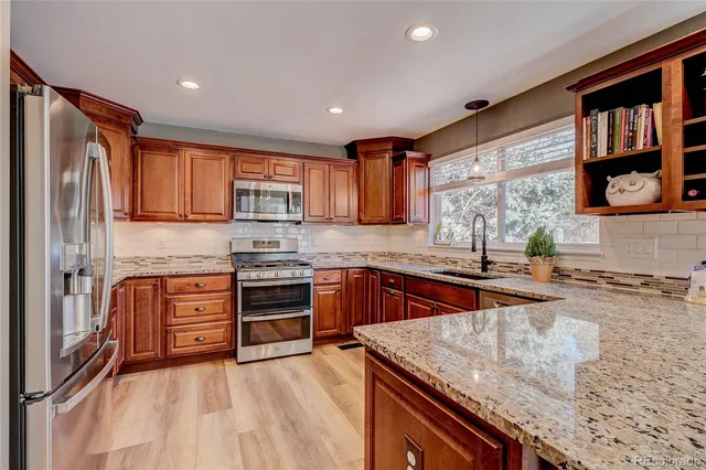 a kitchen with stainless steel appliances granite countertop wooden cabinets a stove top oven a sink and dishwasher