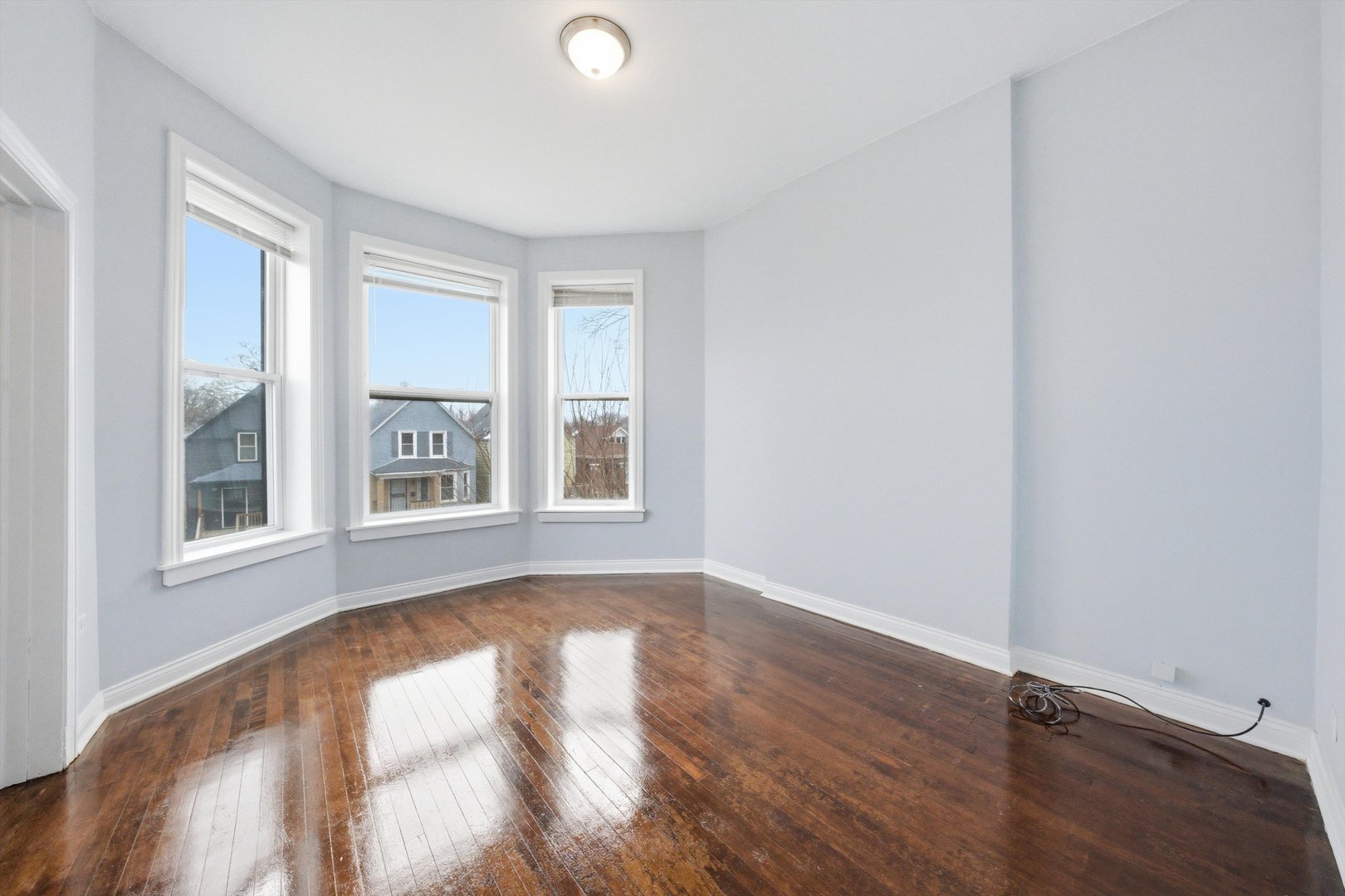 7242 South May Street, Unit 2 Chicago, IL 60621 - Photo 3 of 12 an empty room with wooden floor and windows