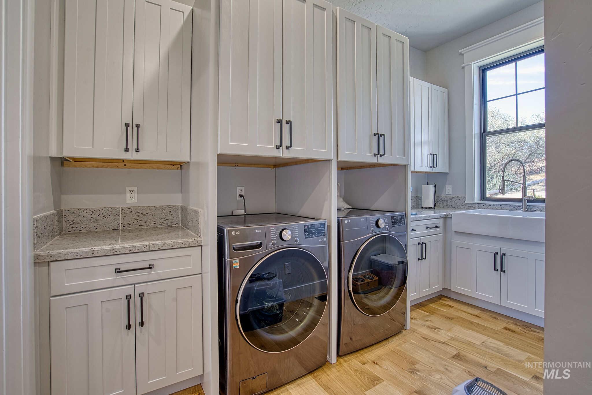 876 Coyote Gulch Road Adrian, OR 97901 - Photo 17 of 50 Built-in cabinetry with shaker-style doors, stone countertops, wood-finish flooring, and an integrated farmhouse sink with a gooseneck faucet