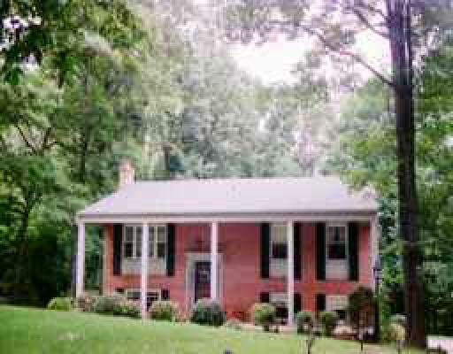 a view of a brick house with a big yard and large trees