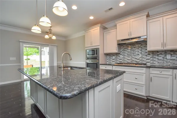 a kitchen with kitchen island granite countertop a sink a center island and cabinets