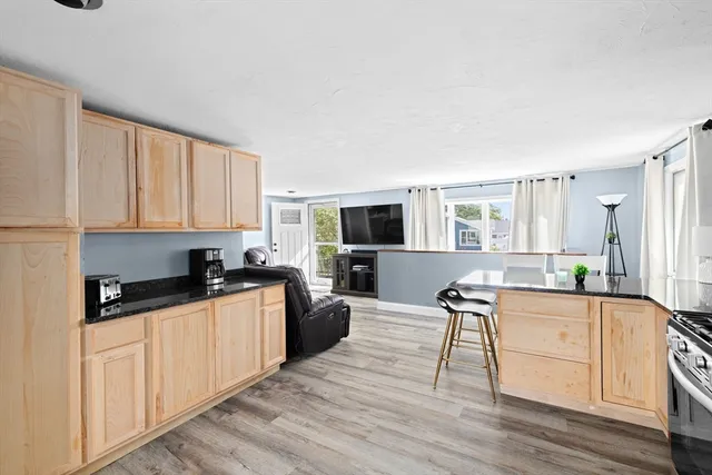 a kitchen with granite countertop a stove top oven a sink dishwasher and white cabinets with wooden floor