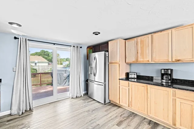 a kitchen with granite countertop a refrigerator a sink and wooden cabinets