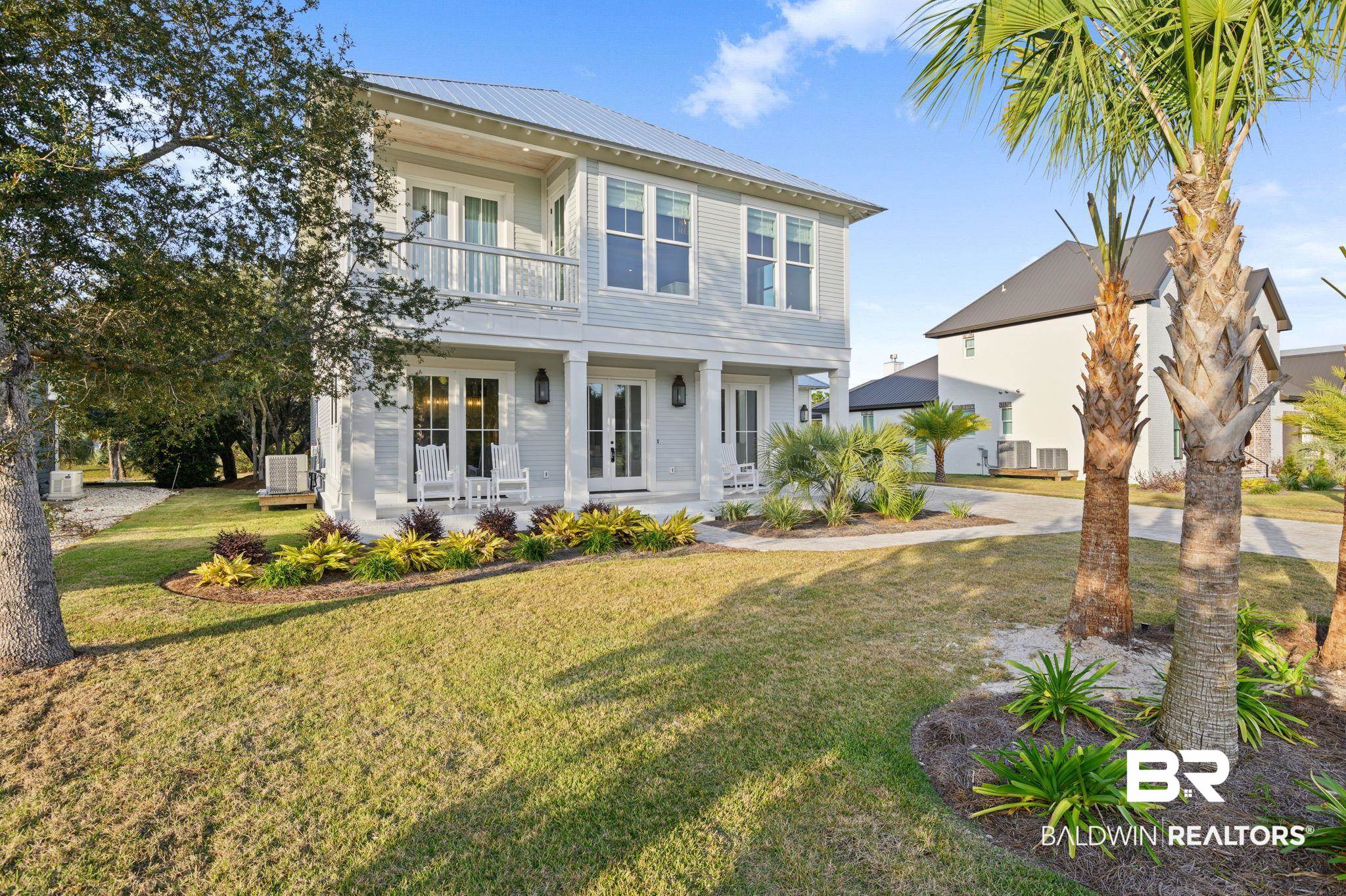 30313 River Road Orange Beach, AL 36561 - Photo 2 of 50 View of front facade with a front lawn, a metal roof, a balcony, french doors, and a porch