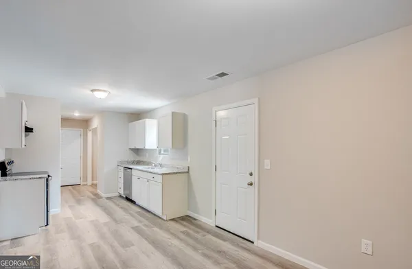 a view of a kitchen with white cabinets and wooden floor