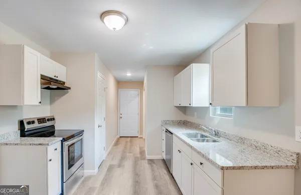 a kitchen with a sink stove and white cabinets