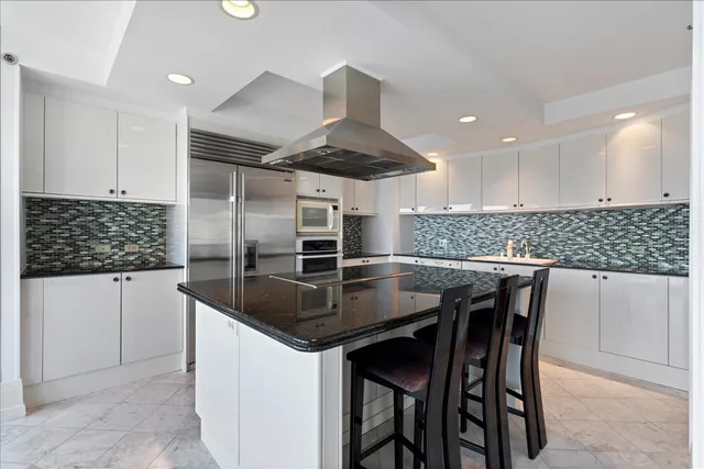 a kitchen with stainless steel appliances granite countertop a stove top oven a sink a dining table and chairs