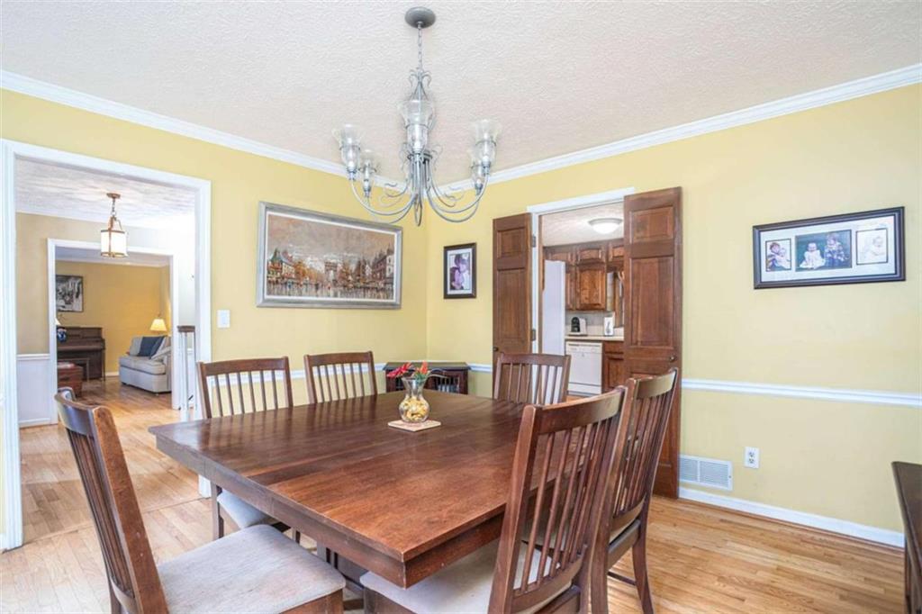 3838 Hunting Ridge Drive Southwest Lilburn, GA 30047 - Photo 8 of 56 a dining room with wooden floor a chandelier a wooden table and chairs