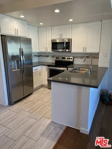 a kitchen with stainless steel appliances granite countertop a refrigerator a stove a sink and a microwave