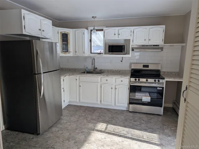 a kitchen with white cabinets and refrigerator