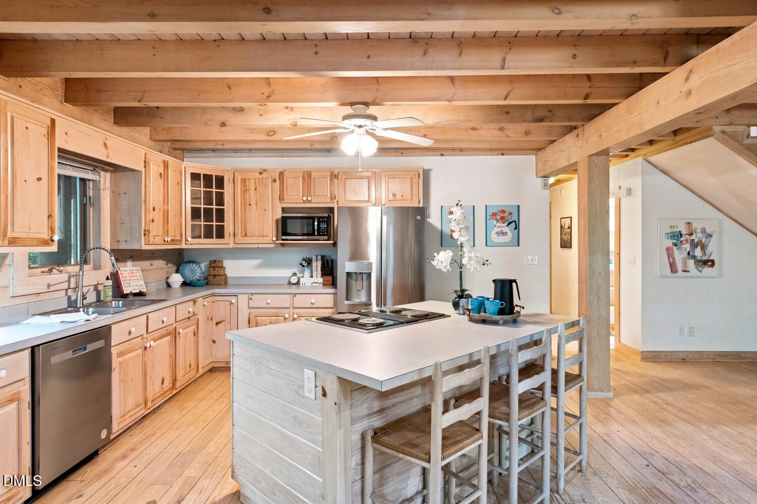 7391 Howerton Road Elon, NC 27244 - Photo 18 of 53 Exposed wood ceiling beams, wood-finish flooring, wood cabinetry, built-in stainless steel appliances, and a central island with a cooktop