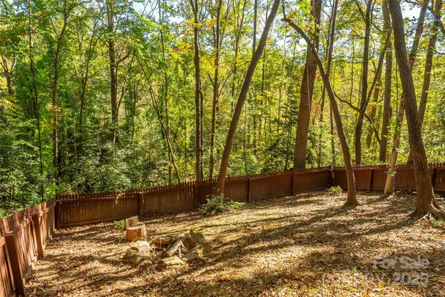 a view of wooden fence and trees in the background