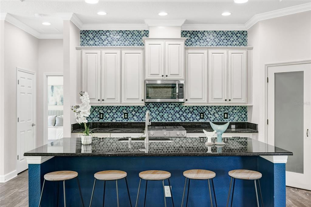5116 Coastal Scene Drive Apollo Beach, FL 33572 - Photo 12 of 36 a kitchen with granite countertop a table chairs stove and cabinets