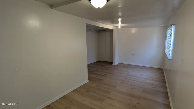 a view of an empty room with wooden floor and a ceiling fan