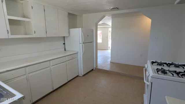 a kitchen with a refrigerator and white cabinets