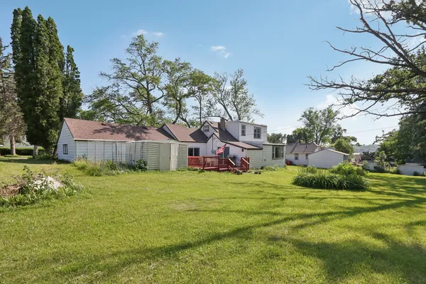 a view of a house with a big yard potted plants and large tree