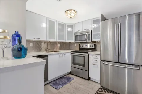 a kitchen with a refrigerator sink and cabinets