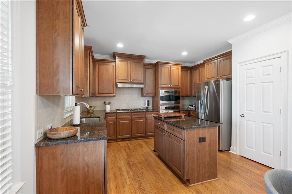 5740 Cascade Trail Cumming, GA 30040 - Photo 19 of 64 a kitchen with stainless steel appliances granite countertop a stove top oven a refrigerator a sink and dishwasher with wooden floor