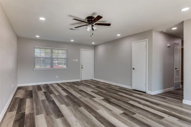 a view of a room with a ceiling fan and hardwood floor