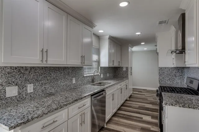 a kitchen with granite countertop a sink stainless steel appliances and cabinets