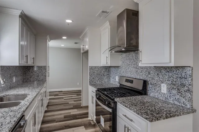 a kitchen with granite countertop a sink stove and cabinets