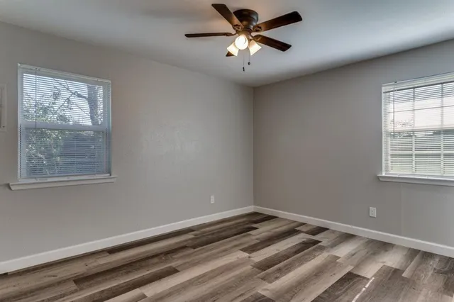 a view of a big room with wooden floor and windows