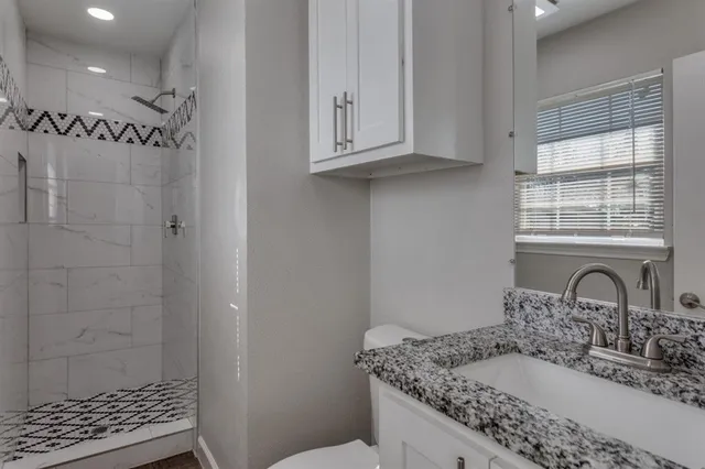 a bathroom with a granite countertop sink a window and shower