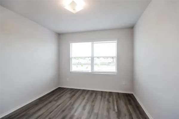a view of an empty room with closet and wooden floor
